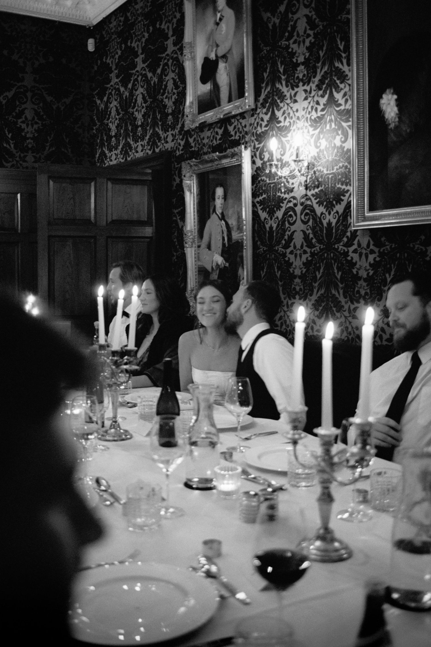 Elegant candlelit dinner table set with fine china and wine glasses in a formal dining room.