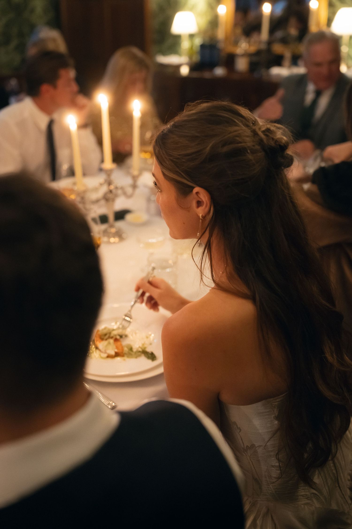 Candlelit dinner scene with guests seated at elegant tables during an evening celebration.
