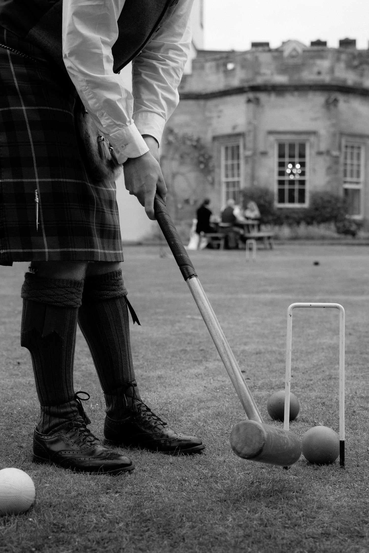 Close-up of traditional croquet mallet and balls with historic castle building in background.