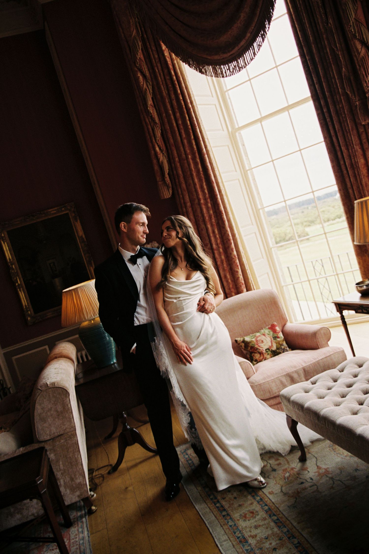 A romantic sequence of wedding photos showing a couple in formal attire posing on an elegant chaise lounge near a window.