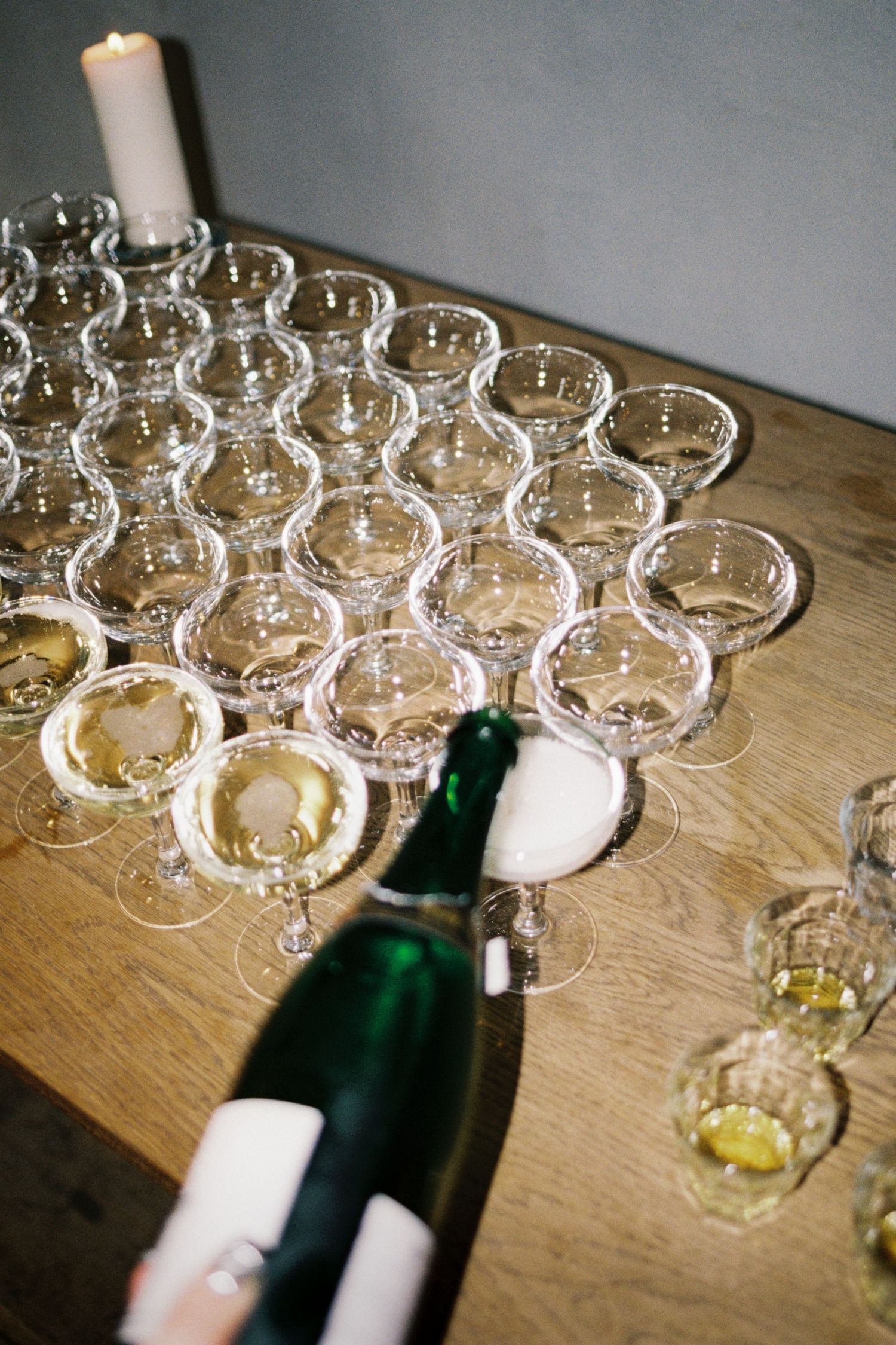 Champagne glasses arranged on wooden table with green bottle ready for pouring at celebration event.
