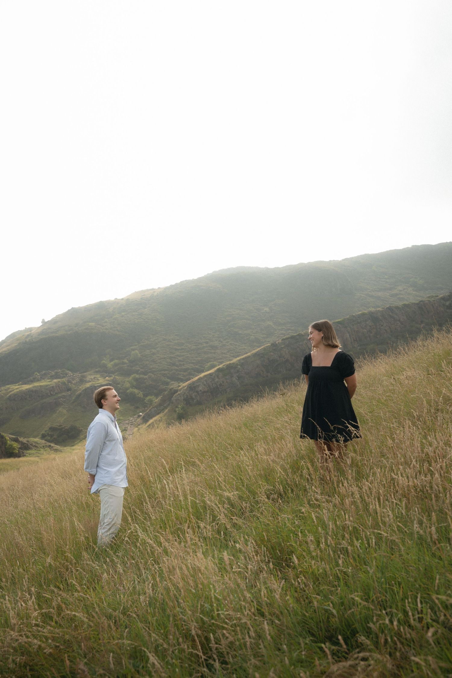 Four scenic views of people standing in tall grass on green rolling hills against an overcast sky during daytime.