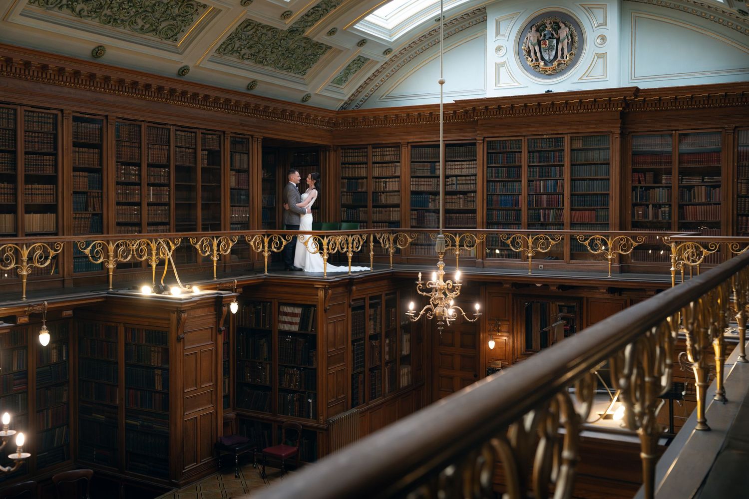 Historic library interior with ornate balcony, wooden bookshelves, and decorative ceiling featuring a wedding couple.