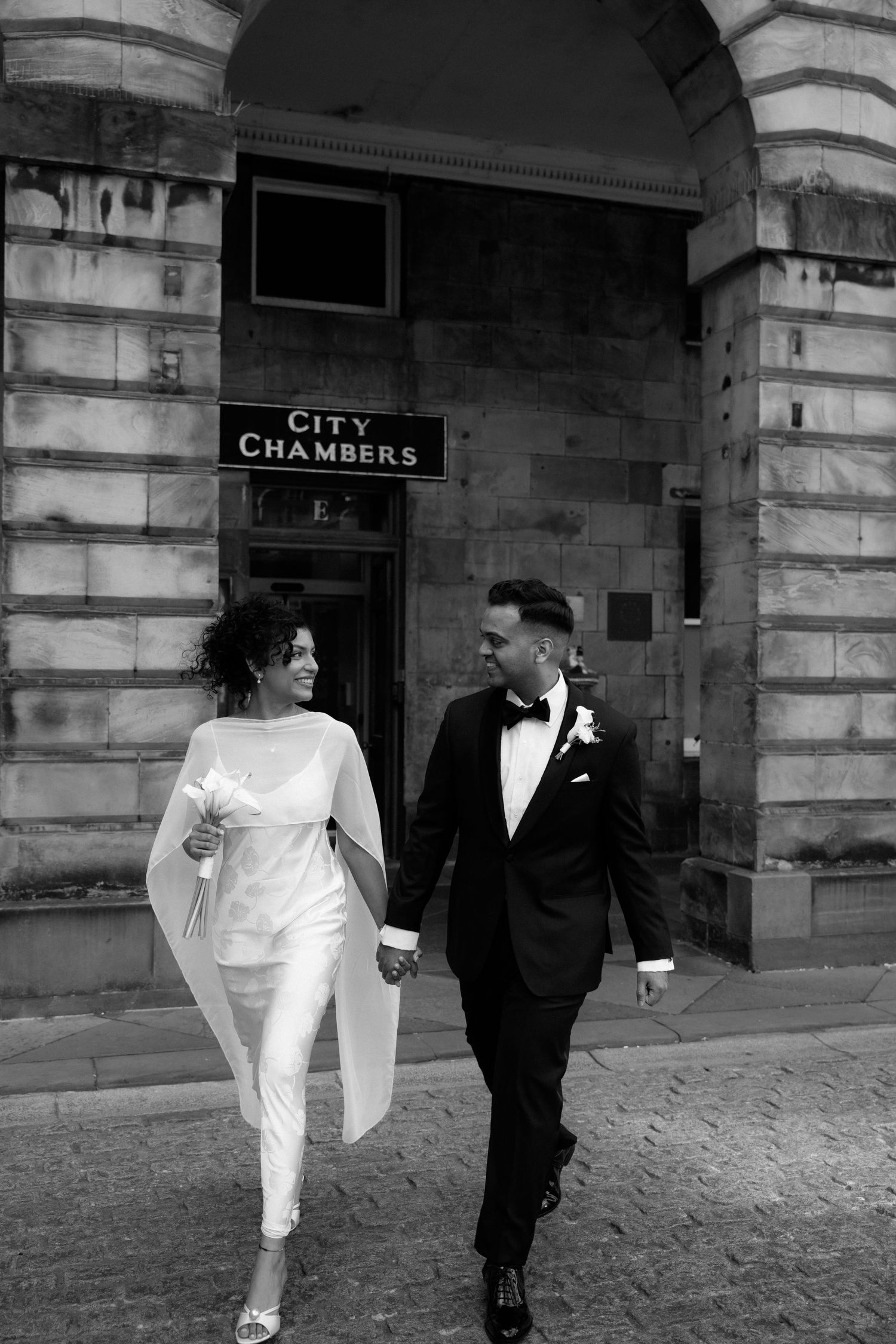 A sequence of four black and white photos showing a couple walking together outside a City Chambers building.