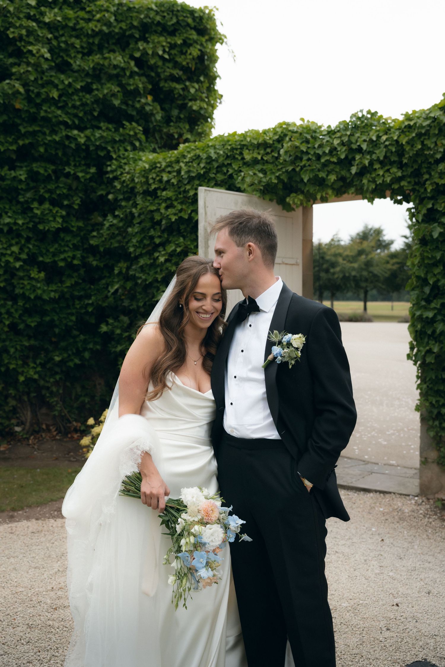 A couple in wedding attire shares intimate moments in a series of romantic outdoor photos against a hedge backdrop.