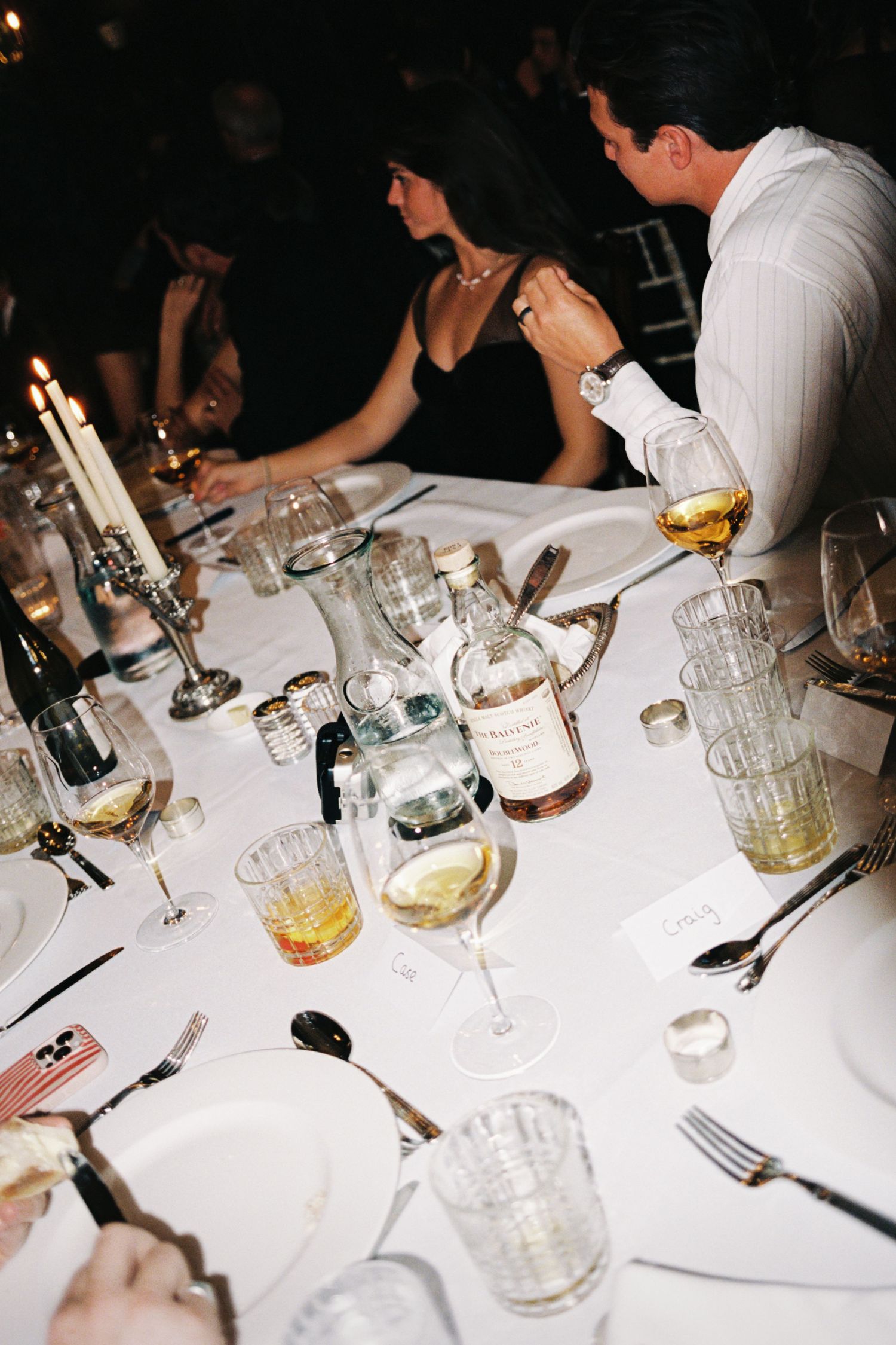 Wedding reception table set with wine glasses and place settings against a dark background.