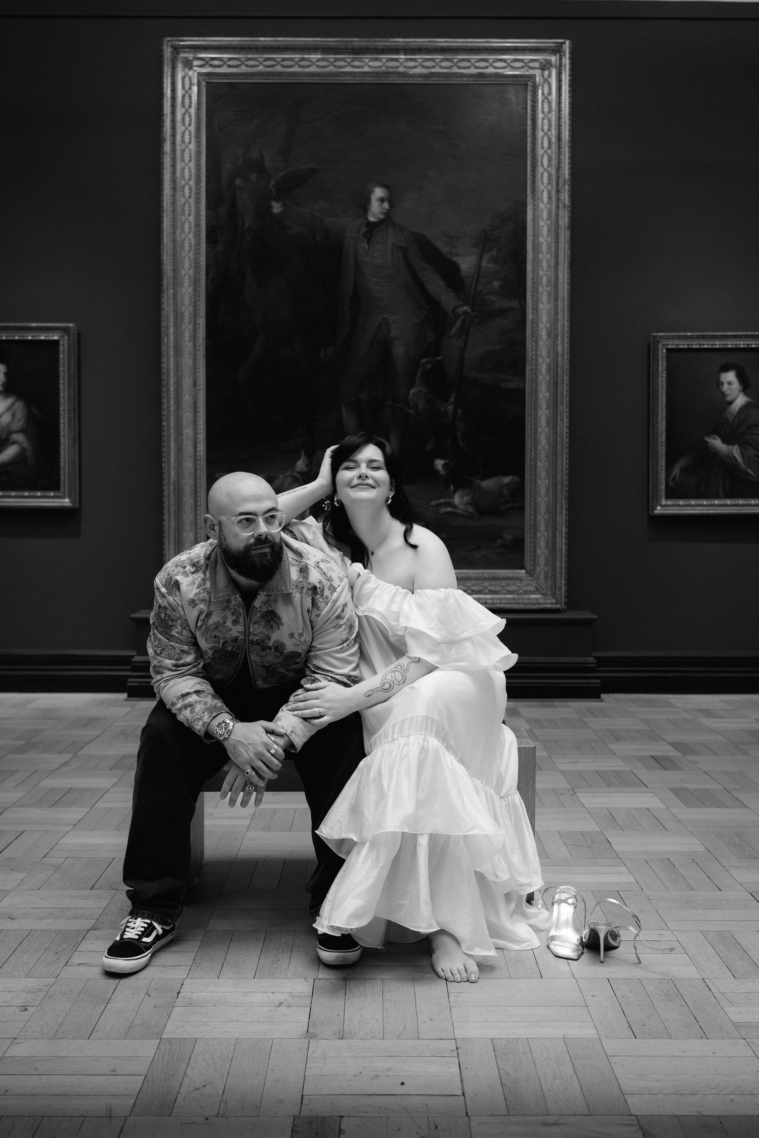 A series of black and white photographs showing people in casual attire sitting and posing on a museum floor.