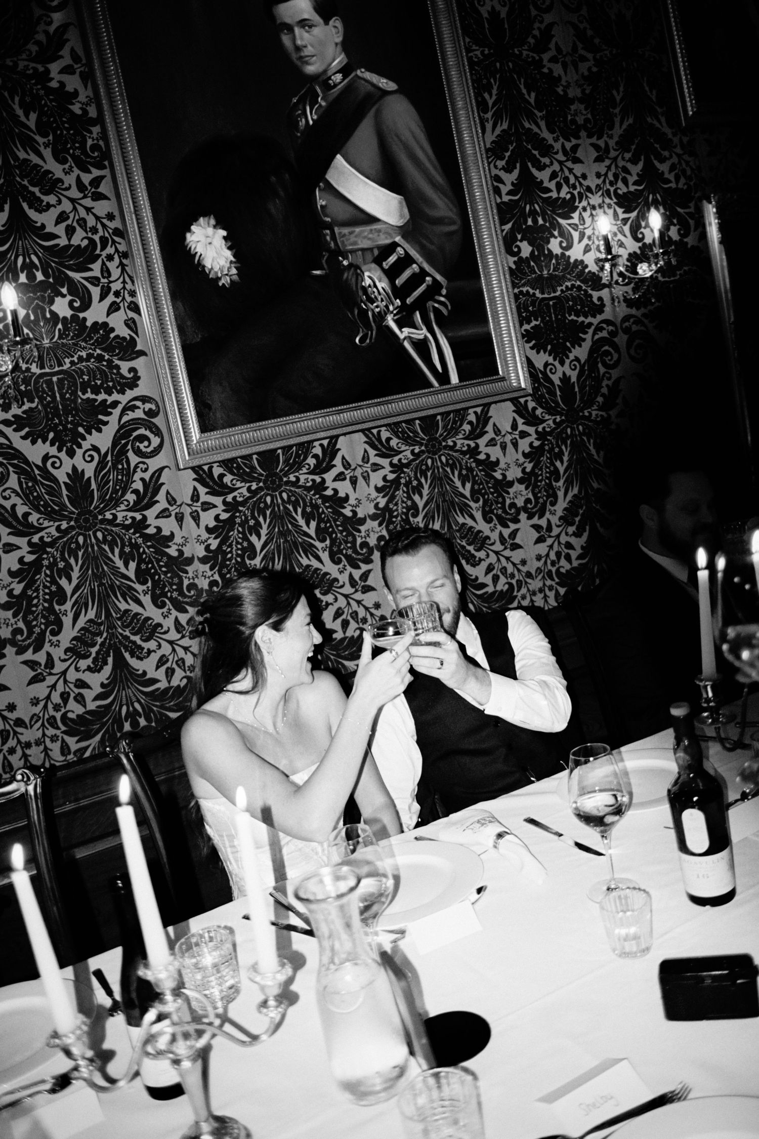 Guests enjoying an elegant candlelit dinner party at a formal table with wine and conversation.