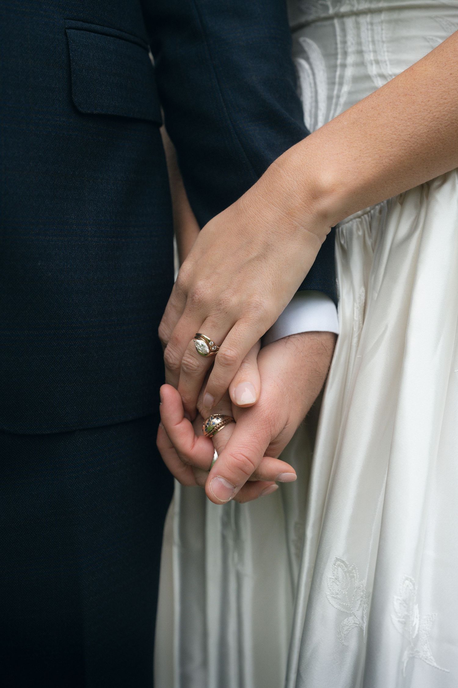 Close-up photo series of two hands holding each other with wedding rings, showing tender moments against black and white attire.