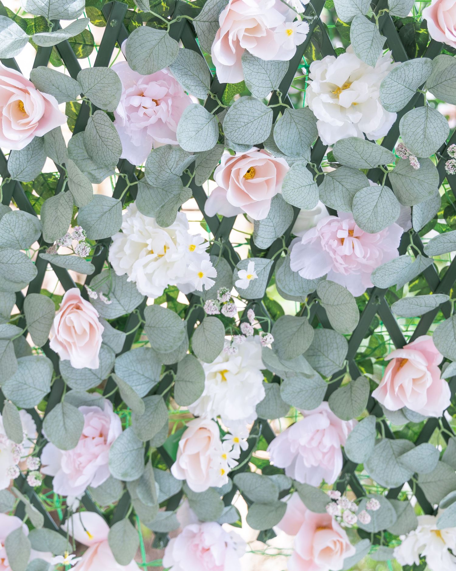 Close-up of a beautiful floral wall arrangement with pink roses and eucalyptus leaves for a wedding.