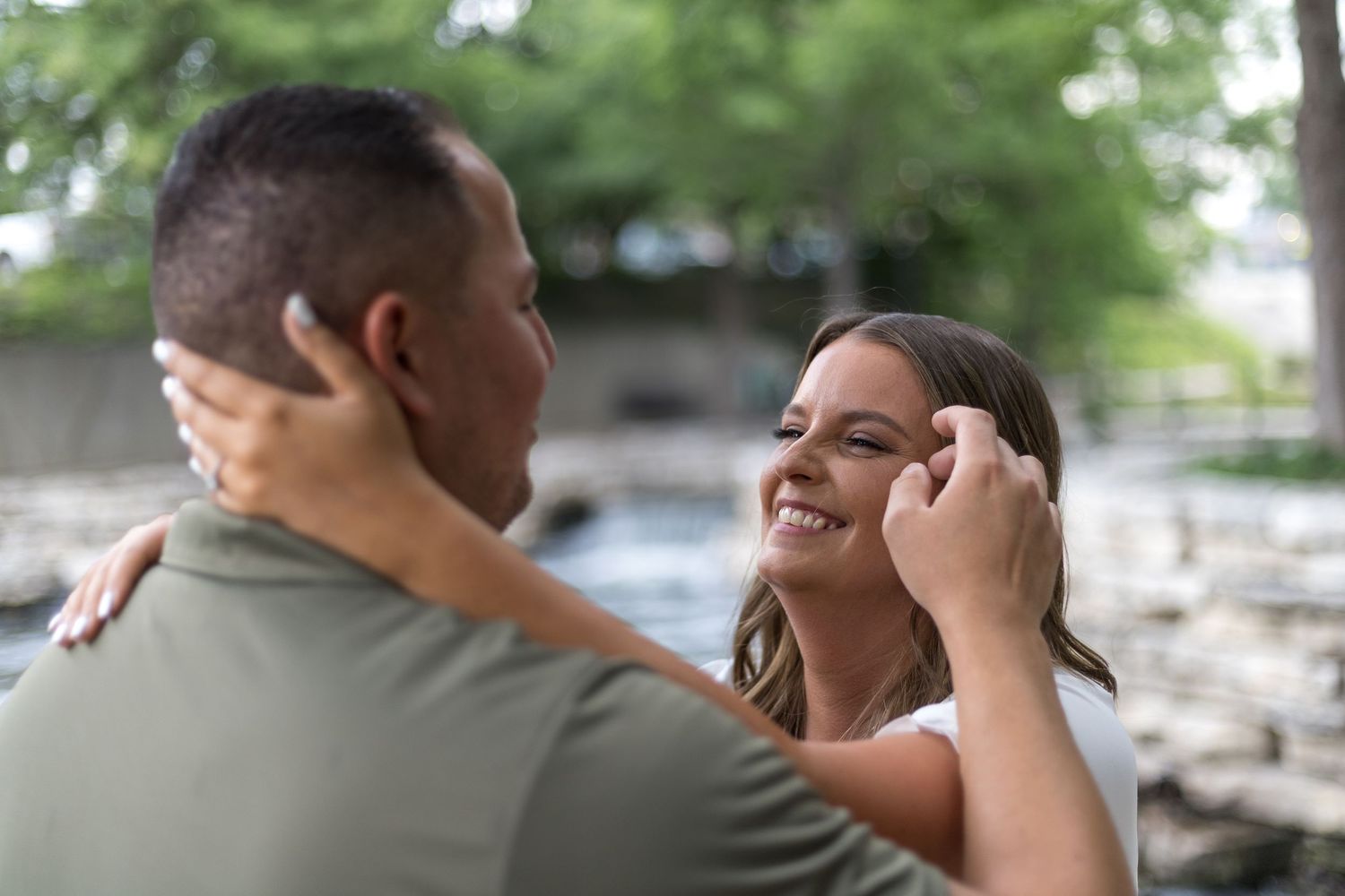 Joyful woman laughing and embracing her partner during a romantic outdoor engagement photo session.