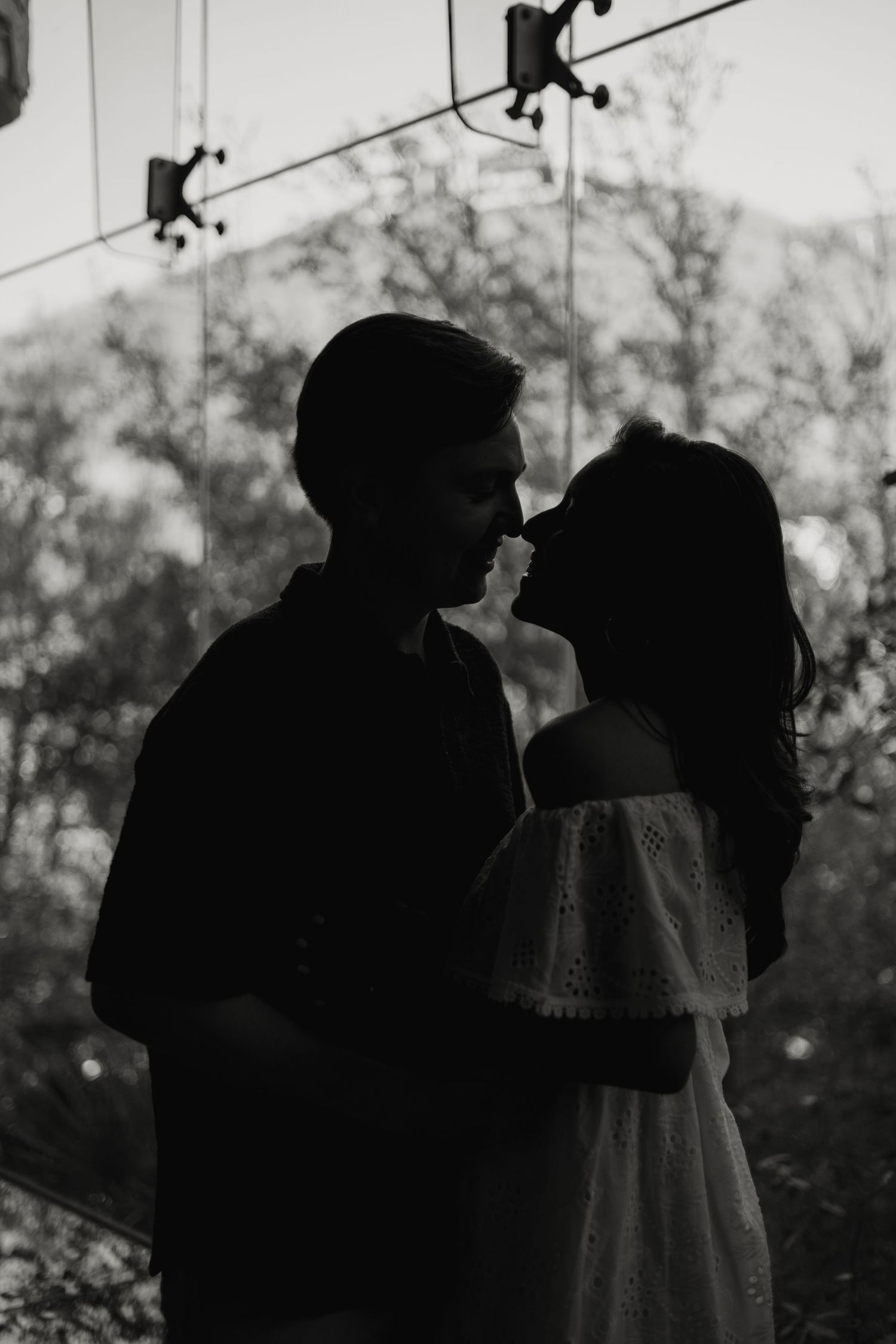 Romantic silhouette of a couple about to kiss against a softly lit outdoor background.