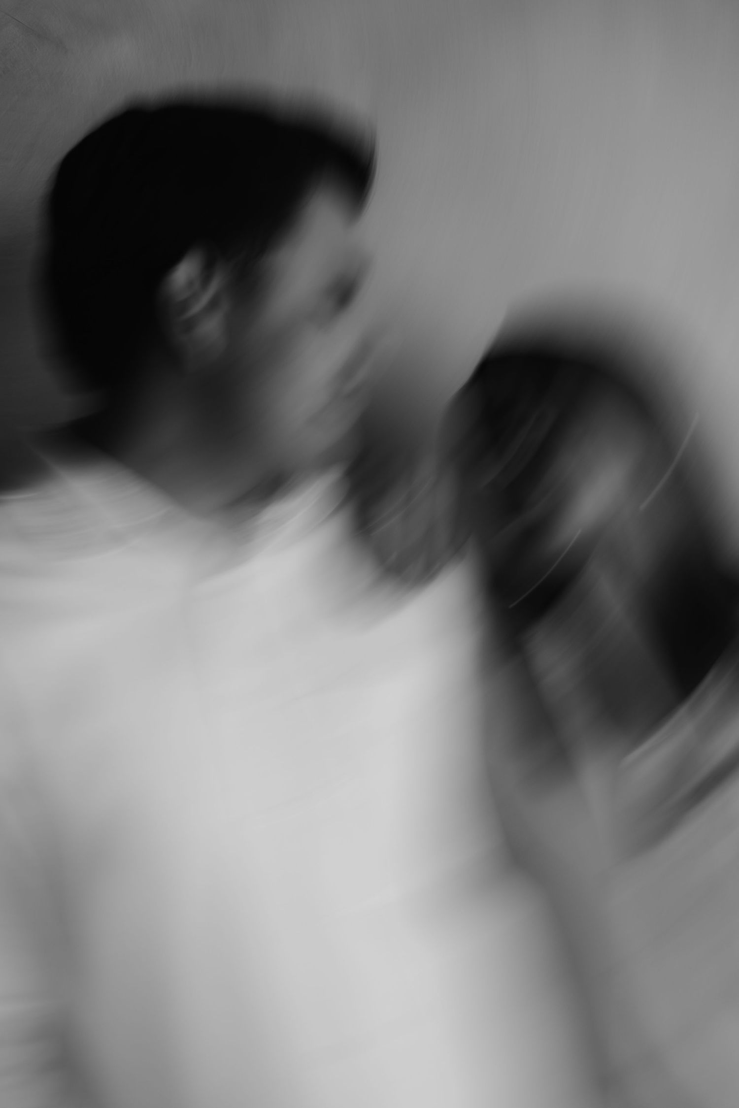 Blurry black and white motion blur photo of two people standing close together, artistic abstract photography.