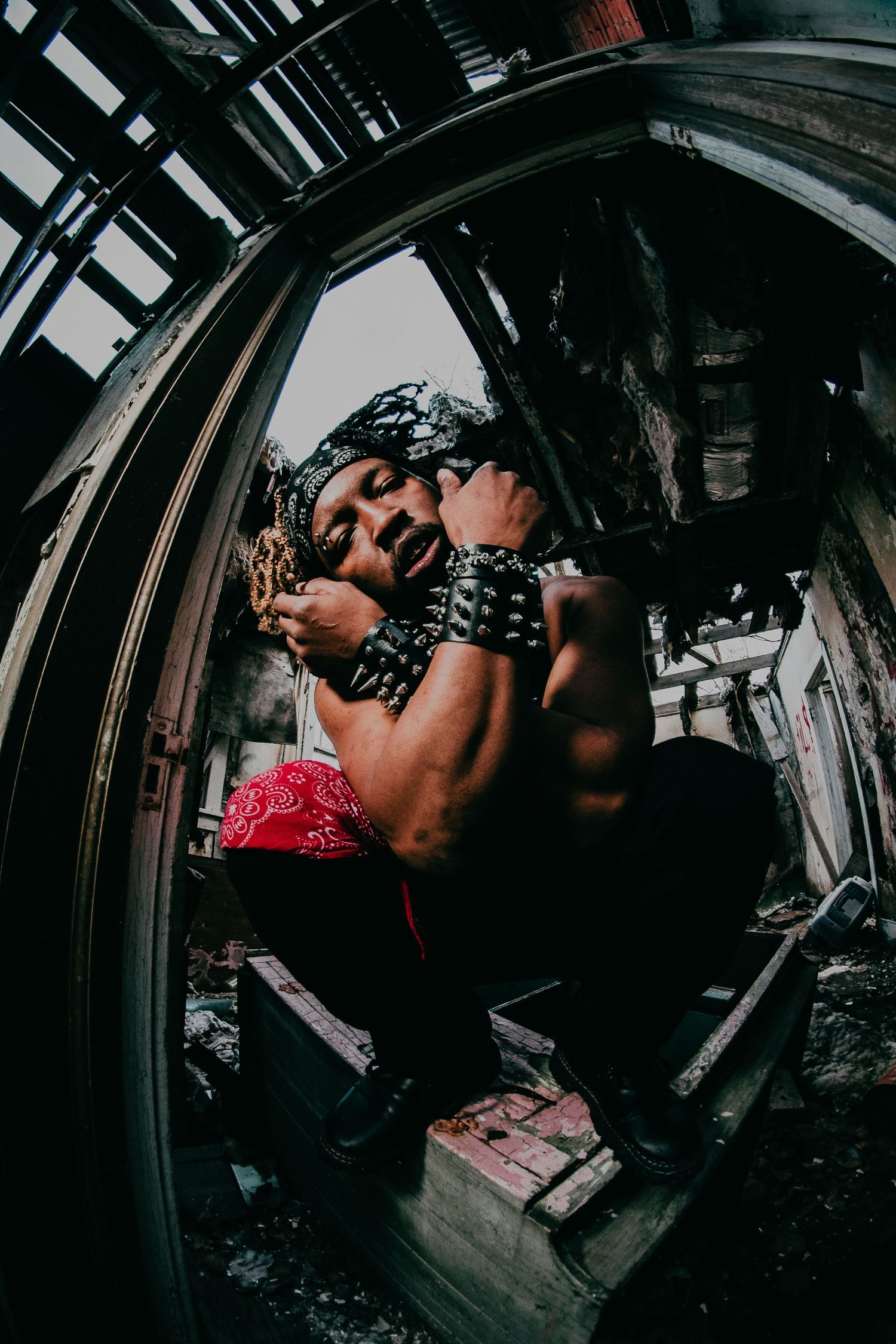 Fisheye style portrait of Jang the Goon crossing his arms in an abandoned building