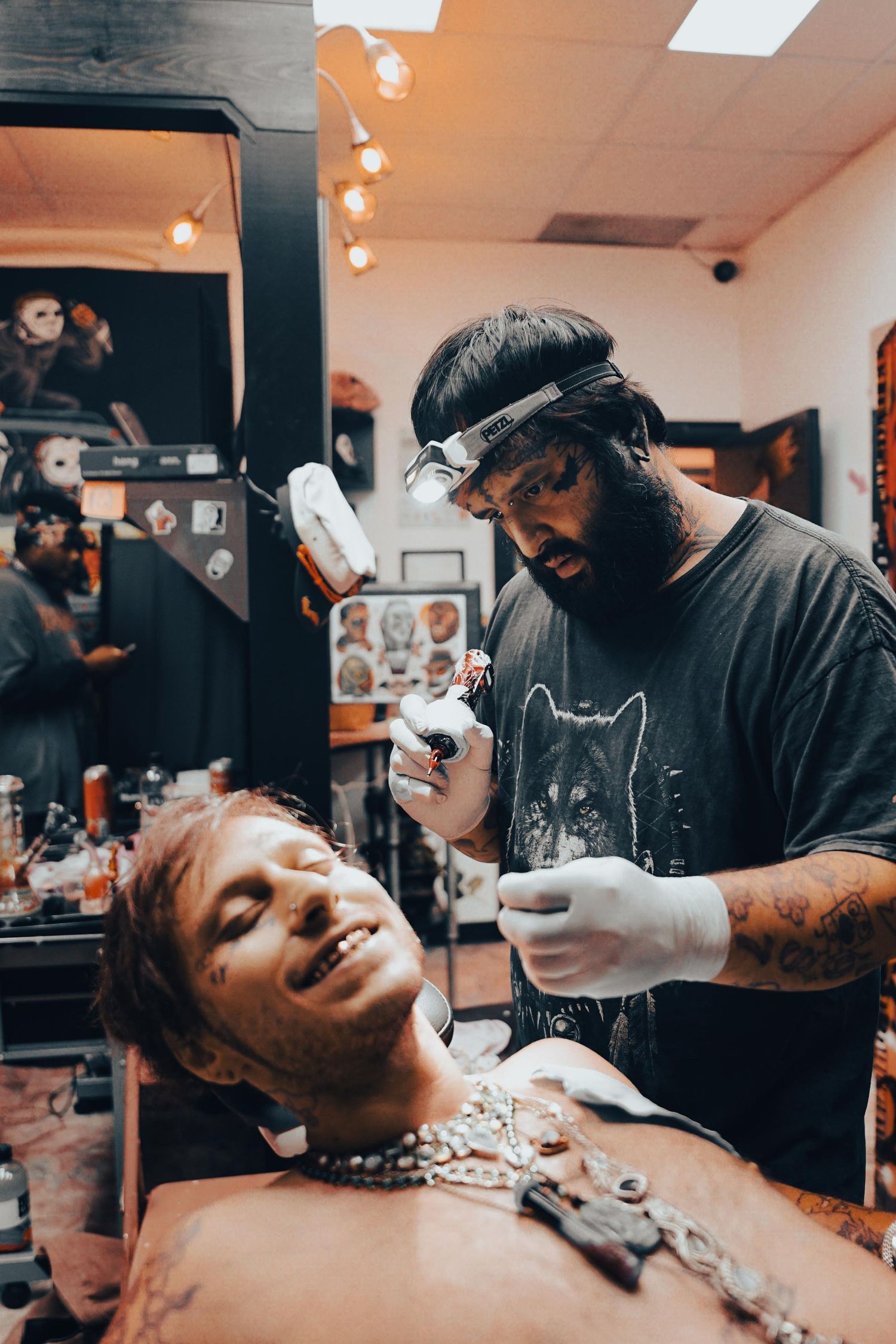 Candid moment of tattoo artist tattooing someone's face in a small tattoo shop
