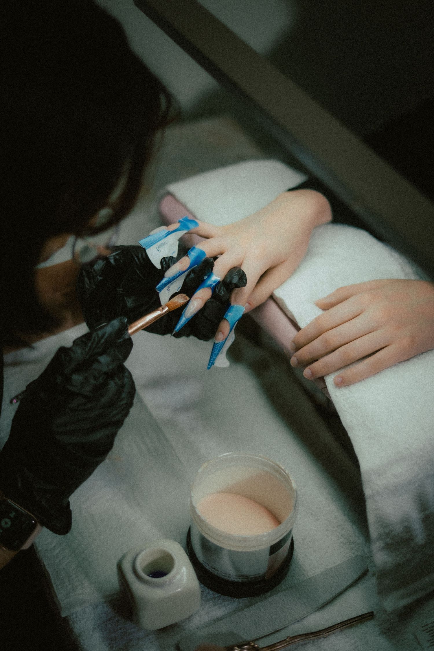 A close up shot of a nail artist painting on a clients nails