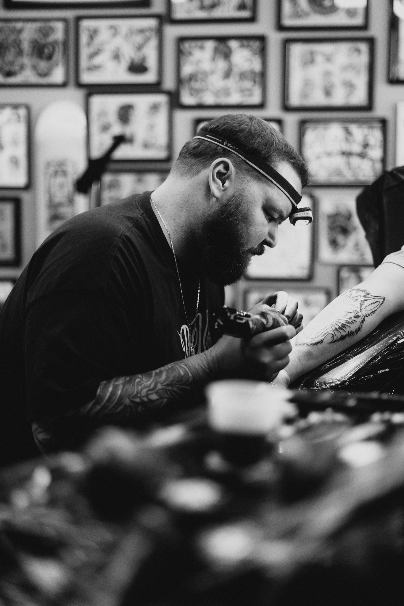 Black and white image of tattoo artist focusing on the art he is tattooing on a client