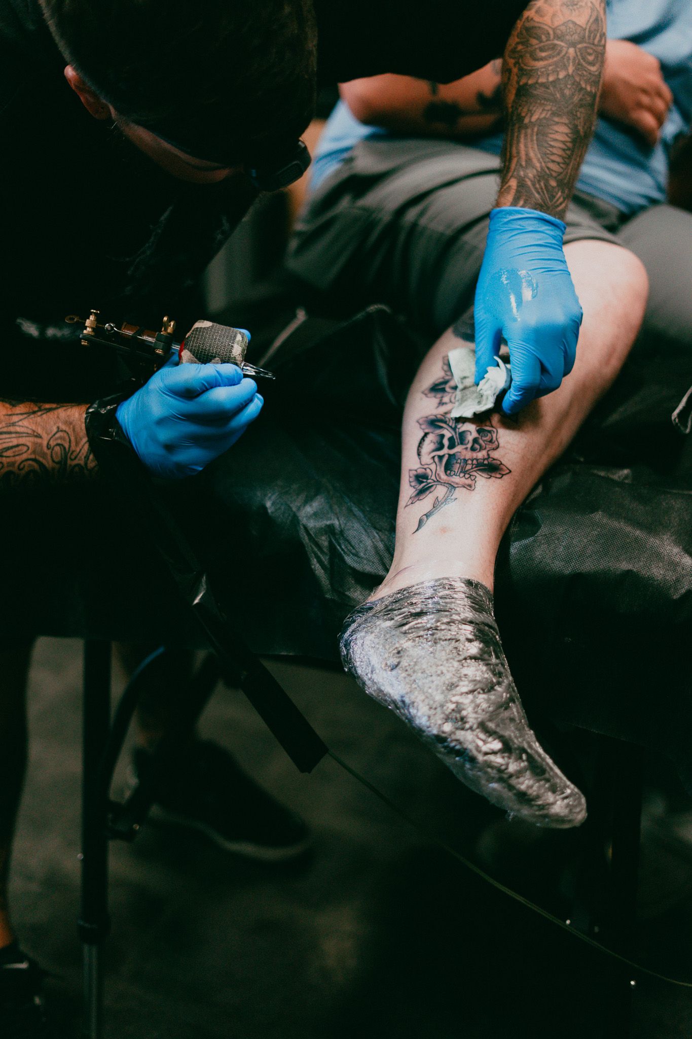 A tattoo artist working on a leg tattoo