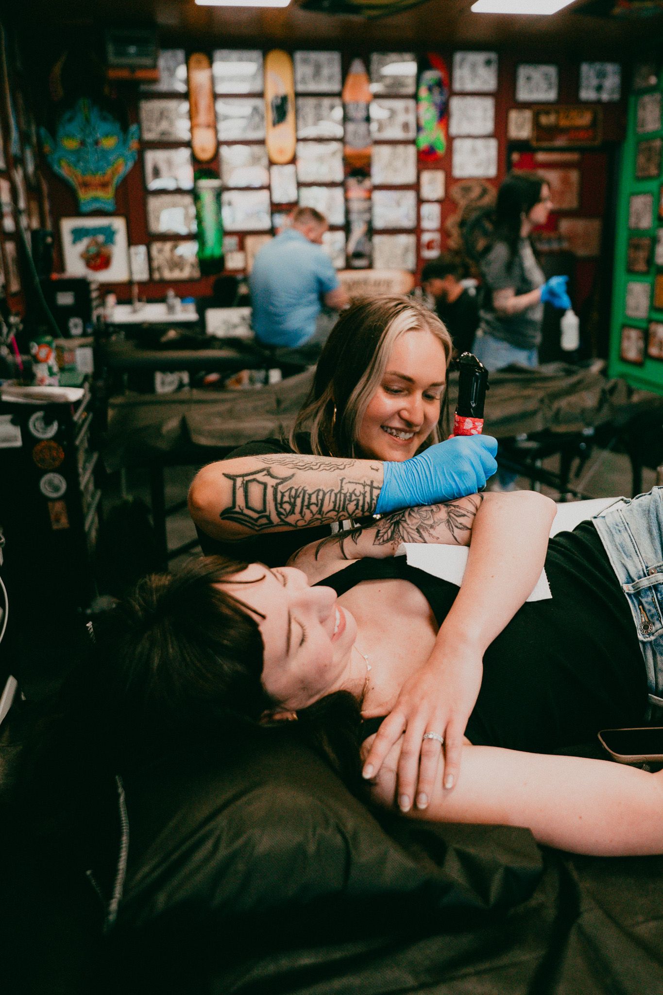 Tattoo artist smiling while tattoo a woman's arm