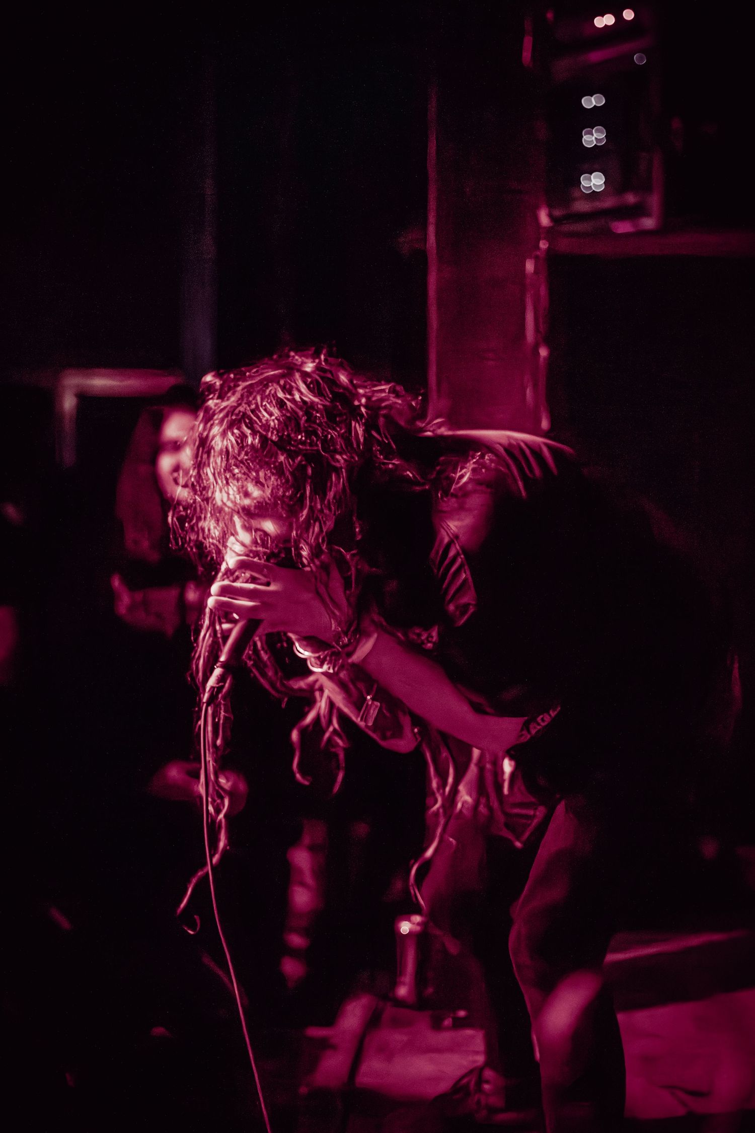 A very pink photo with a man screaming into a microphone