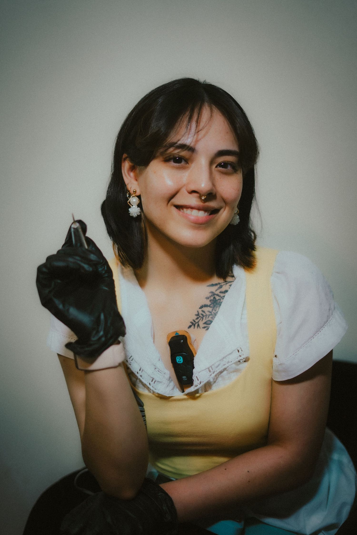 A portrait of a woman in a yellow shirt holding up a nail tool