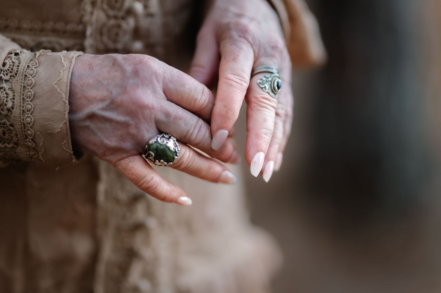 Close-up of elderly hands adorned with large statement rings, including a dark gemstone and turquoise silver ring.