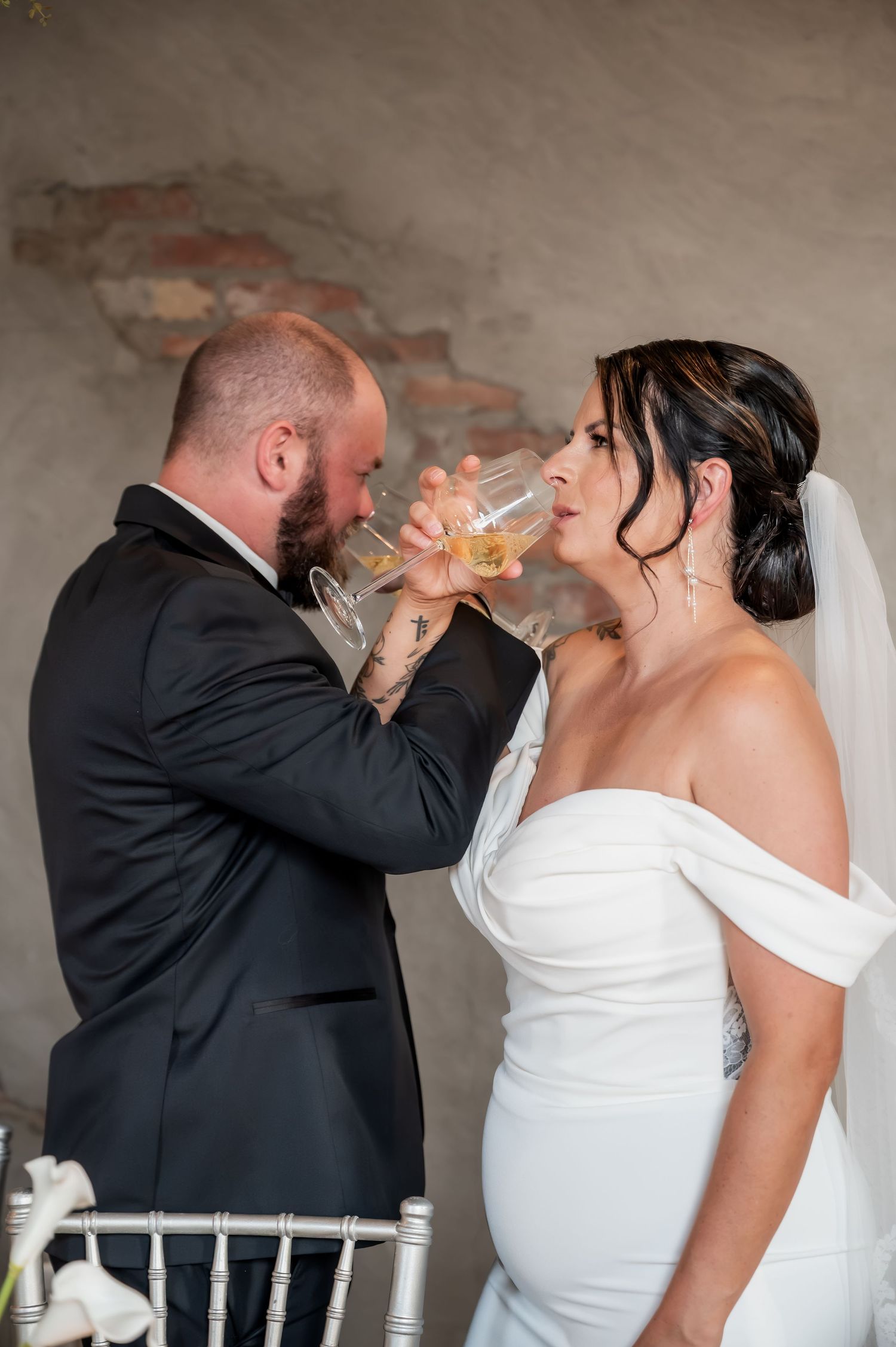 Bride and groom share a champagne toast, crossing arms in a romantic wedding tradition.