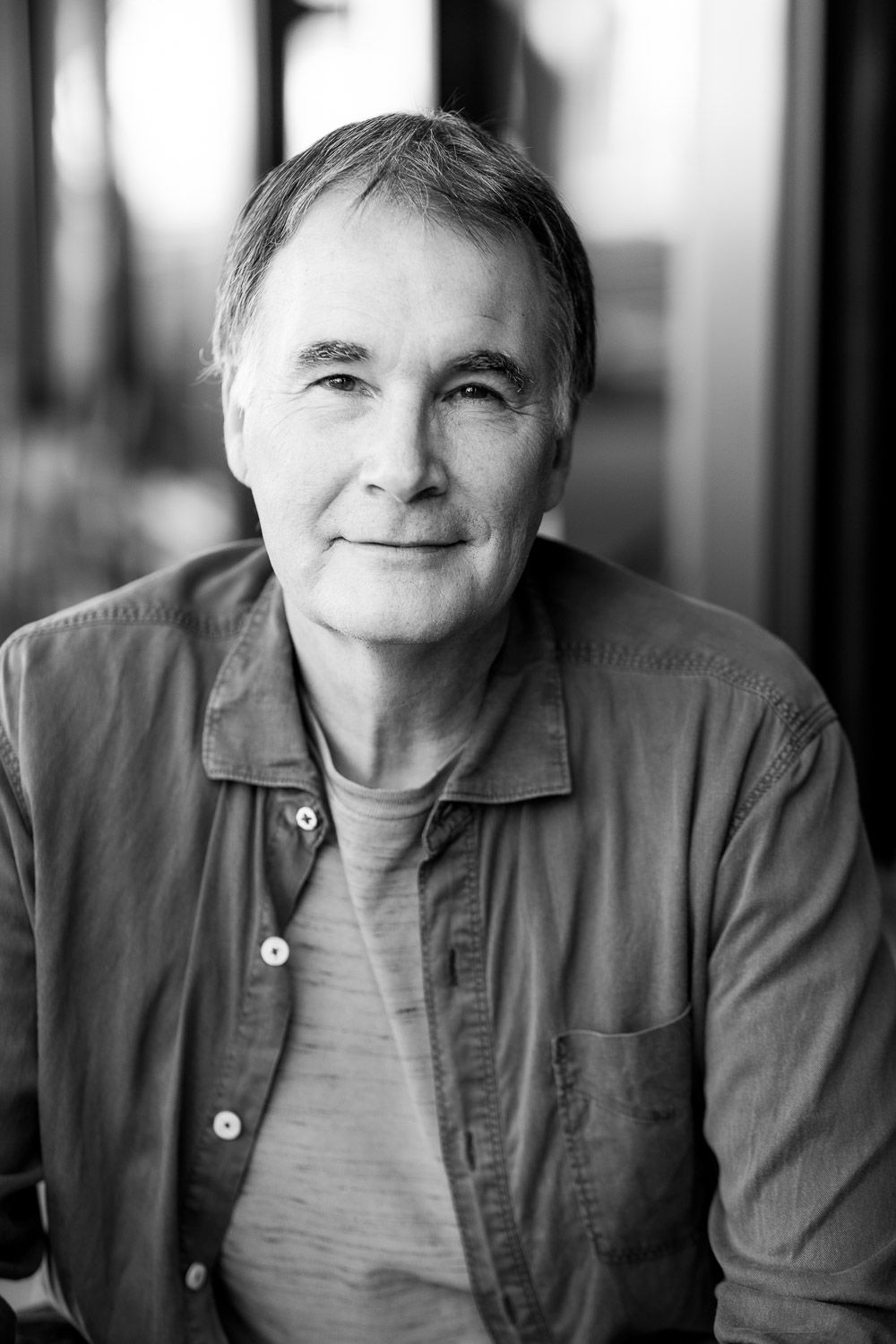 Black and white portrait of Steve Hull, a middle-aged photographer with gray hair wearing a casual button-up shirt, smiling softly.