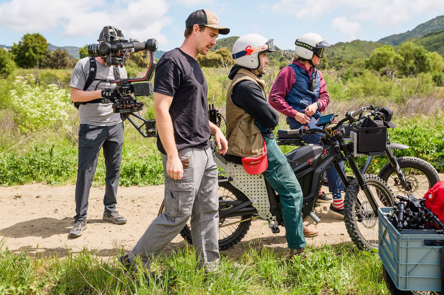 Film crew testing a camera stabilization rig to produce content outdoors with electric bikes on a scenic trail location.