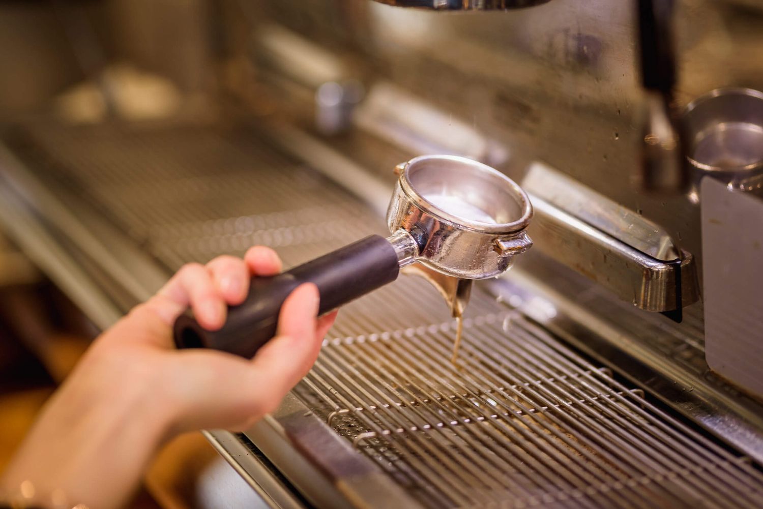 Barista inserting portafilter into professional espresso machine in a coffee shop.