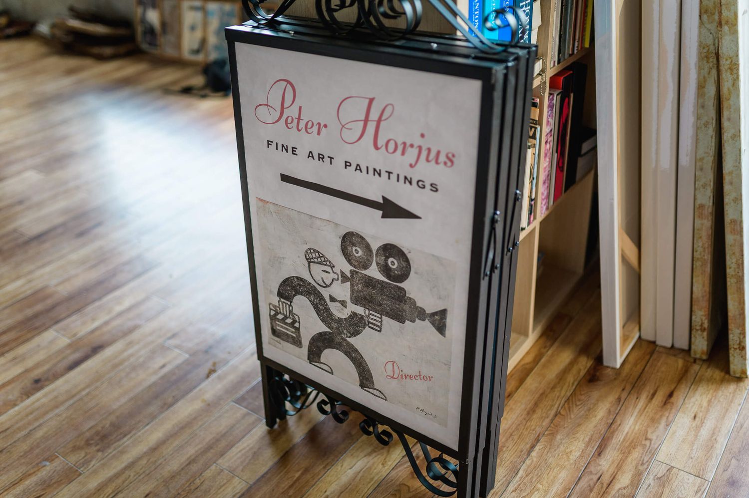 A-frame sign for Peter Horjus Fine Art Paintings displayed on hardwood floor inside an art gallery.