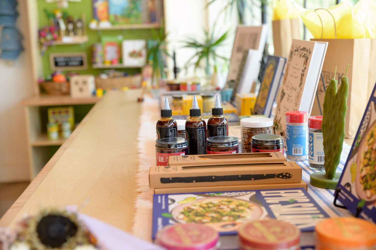 Art supplies and ink bottles arranged on a wooden counter in a colorful craft studio with shelves in background.