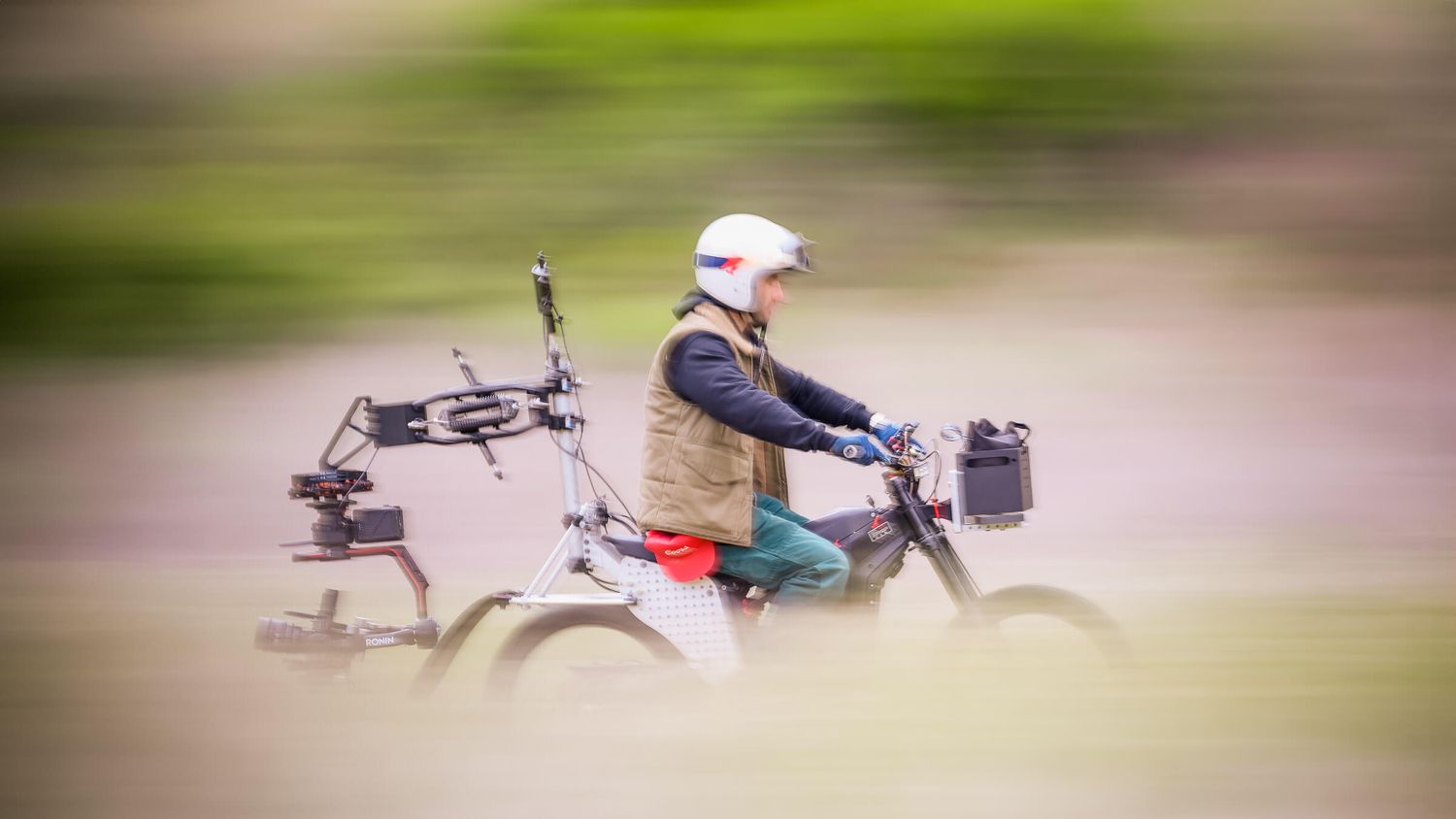 Person riding a motorized bike with camera equipment at high speed, captured with motion blur effect.