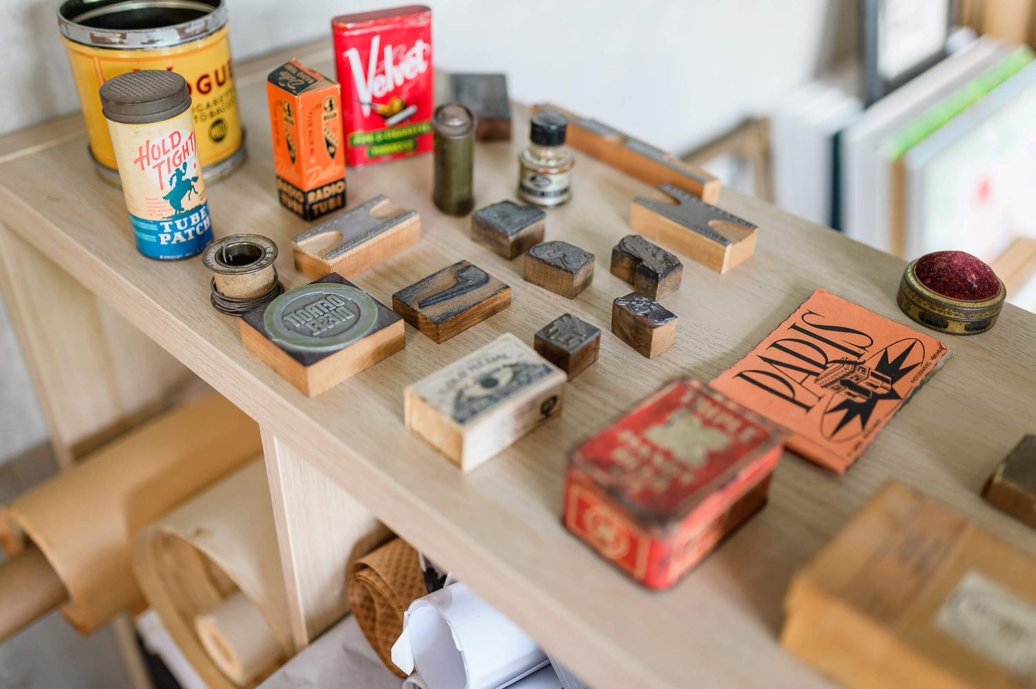 Vintage rubber stamps and antique tins displayed on a wooden table in a craft workspace.
