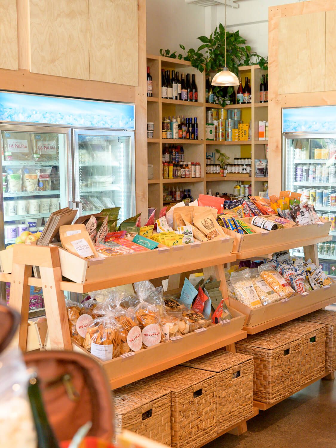 Cozy specialty grocery store with wooden shelves displaying packaged foods, snacks, and beverages in a warmly lit shop.