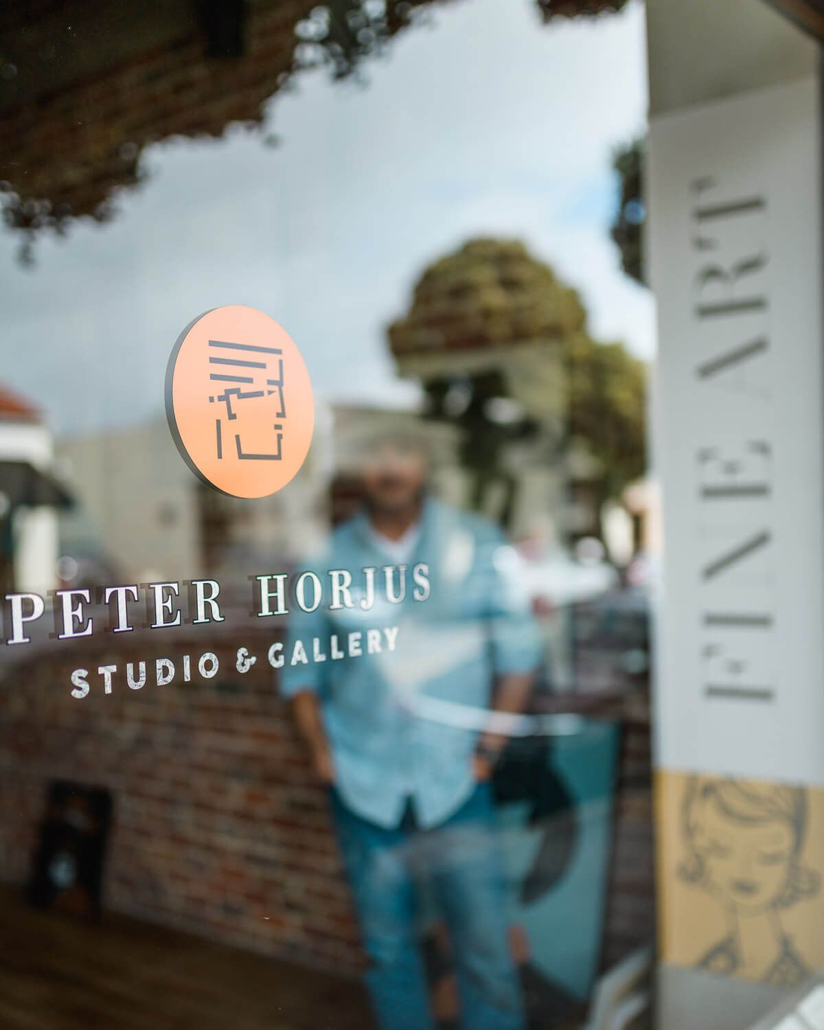 Peter Horius Studio and Gallery fine art storefront window sign reflecting street view outside.