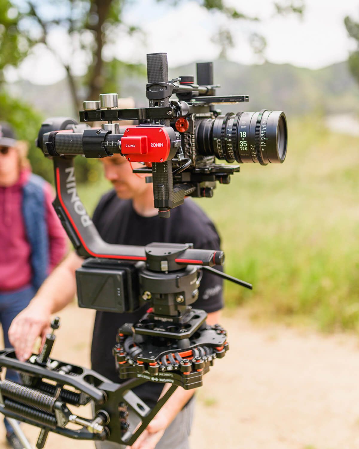 Professional filmmaker operating a camera gimbal stabilizer with a cinema lens on an outdoor film set.