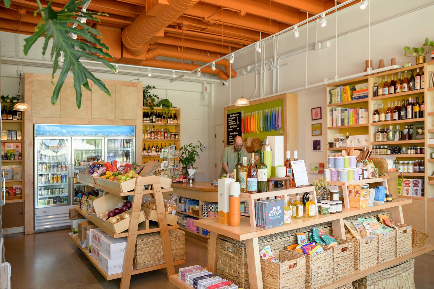 Bright organic grocery store interior with wooden shelves, fresh produce, refrigerated drinks, and colorful packaged goods.