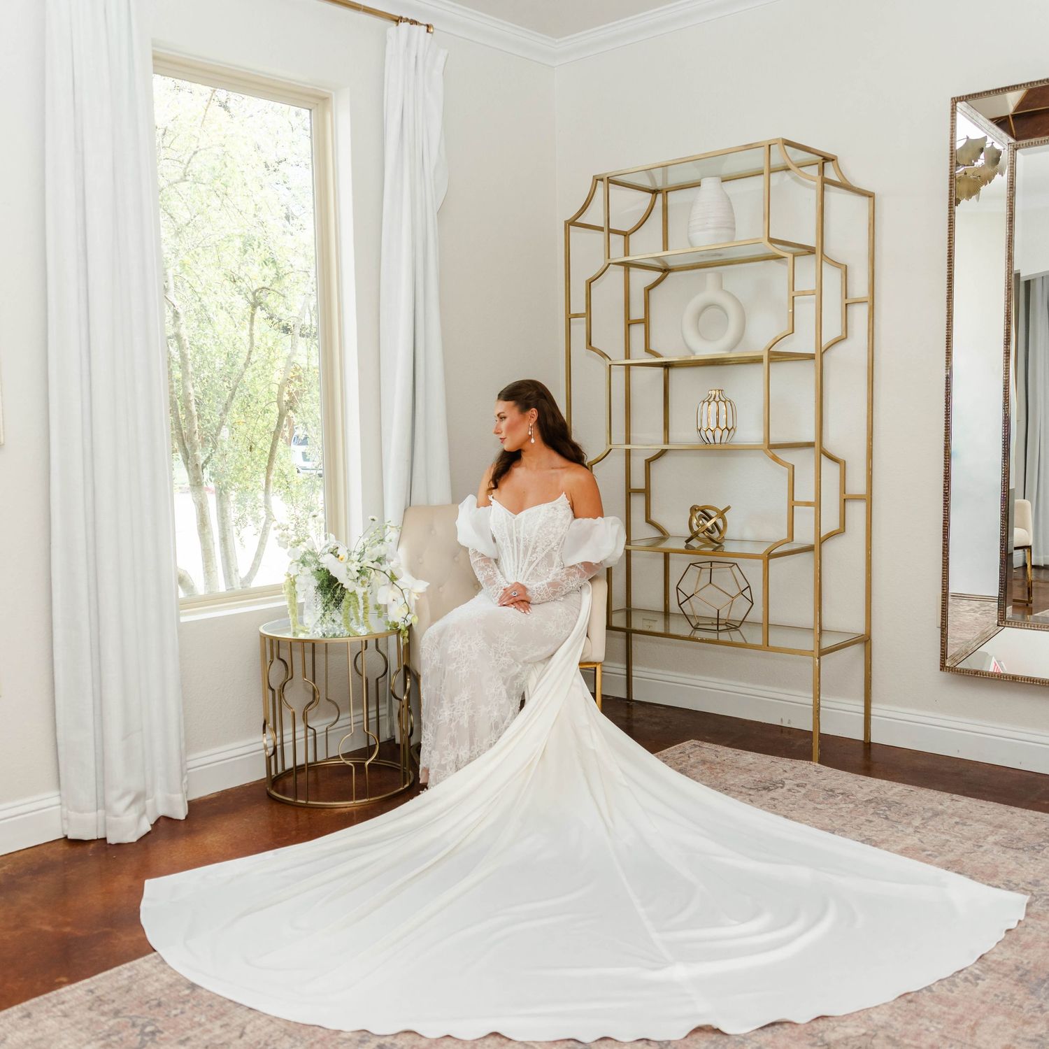 a woman sits next to a window in her bridal gown