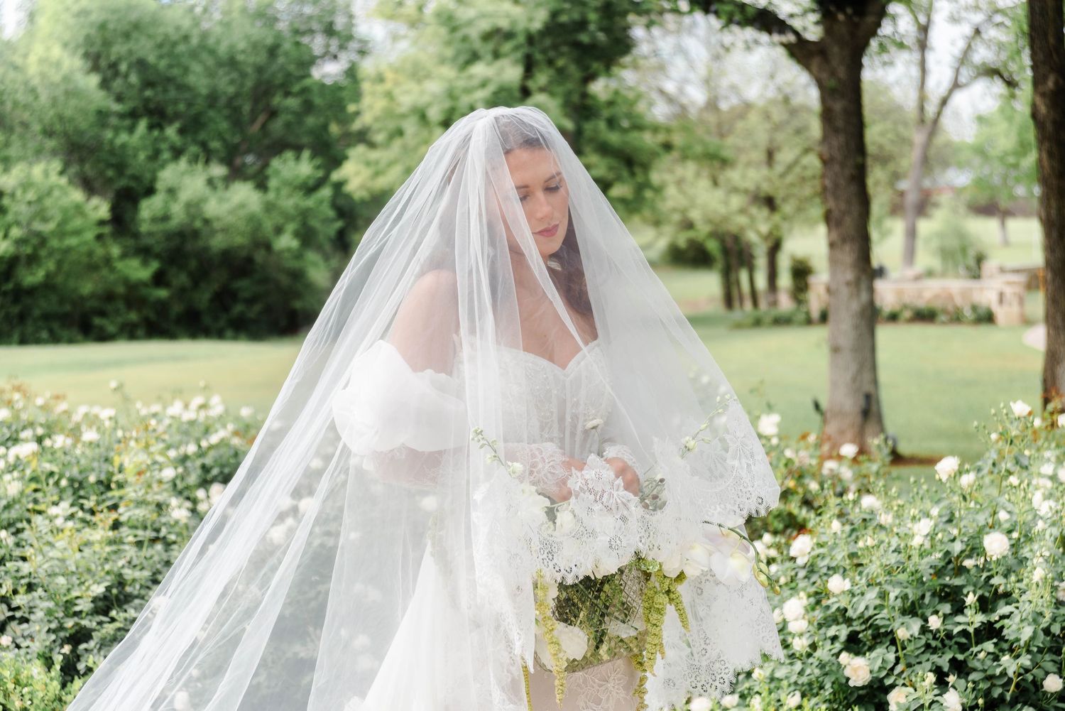 bride posed with the veil over her face holding her bouquet