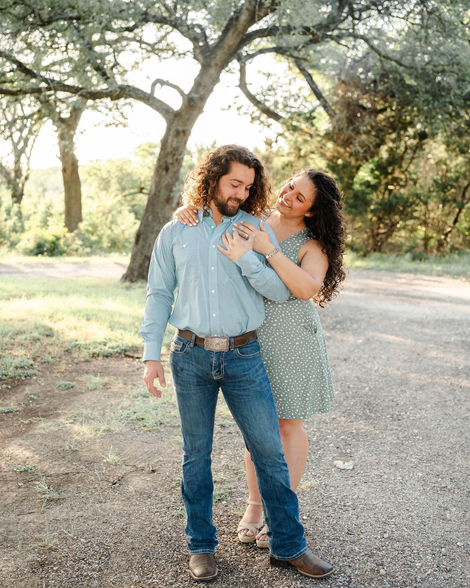 Couple stands together in a tree grove