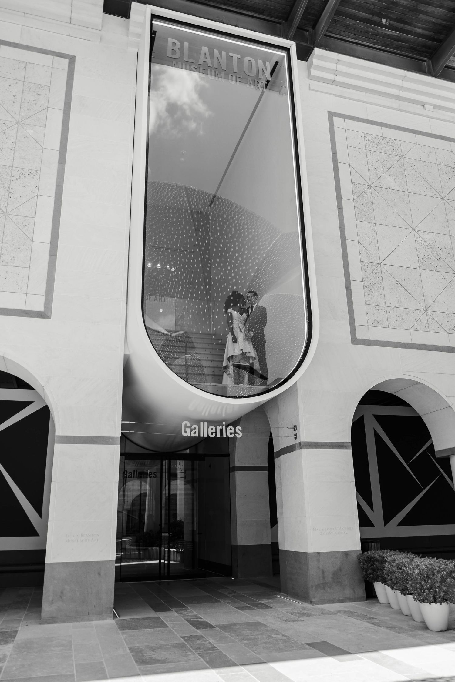 A black and white photograph of the entrance to Blanton Galleries with a large arched window and architectural details.