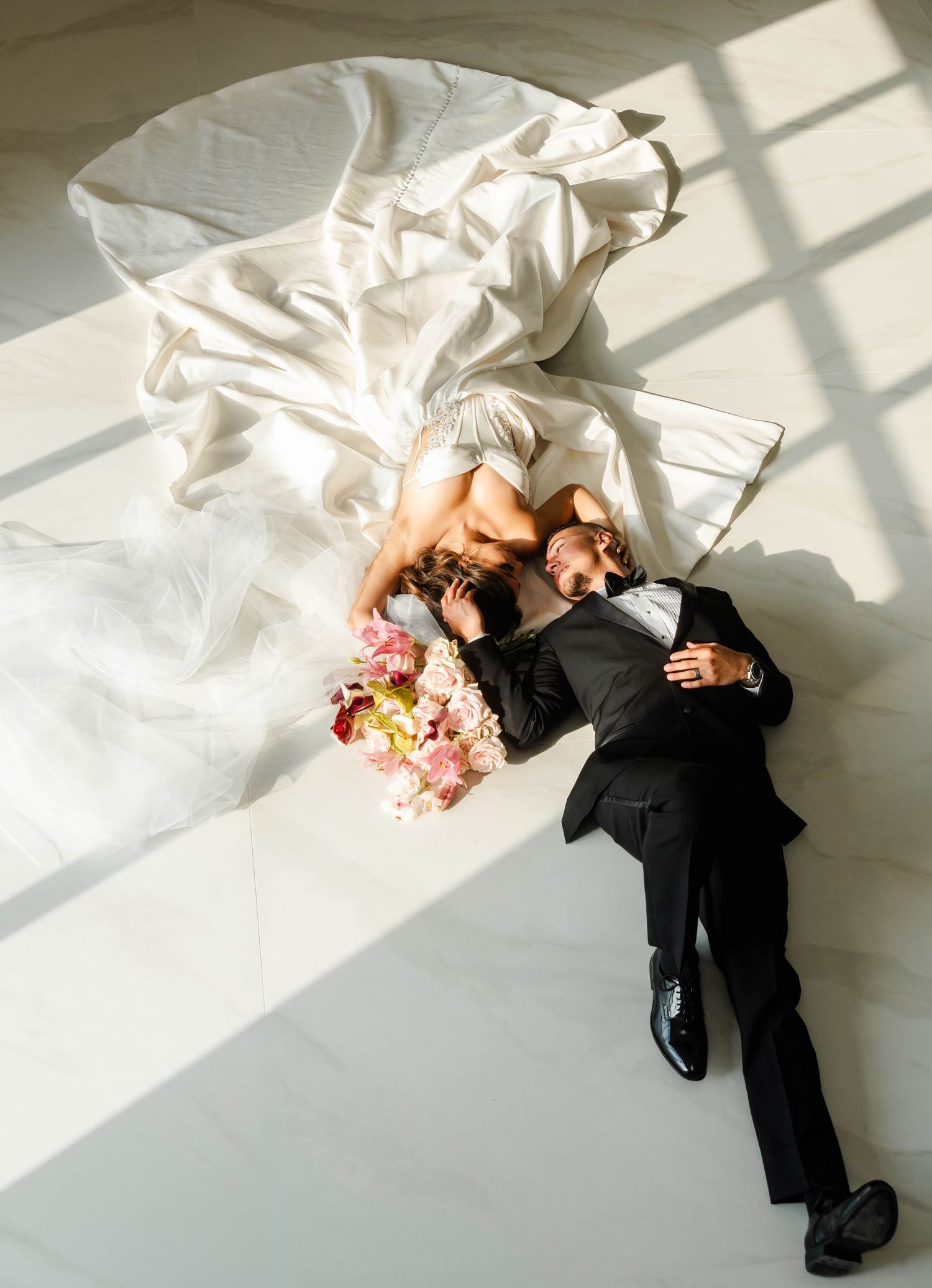 a bride and groom lay posed on the floor