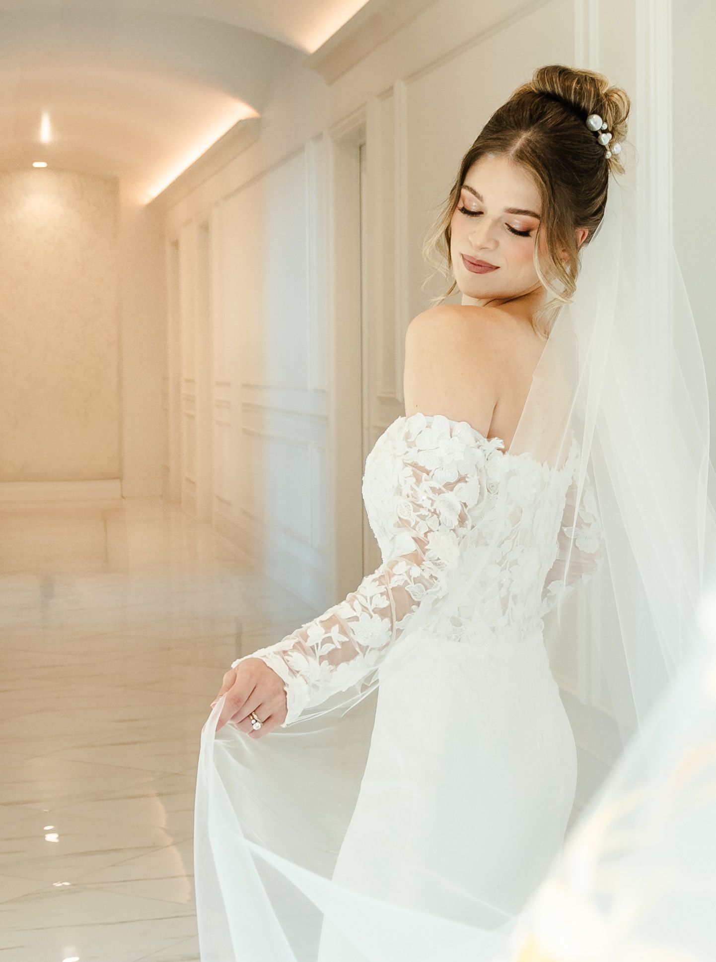 A bride looks over her shoulder holding her veil softly