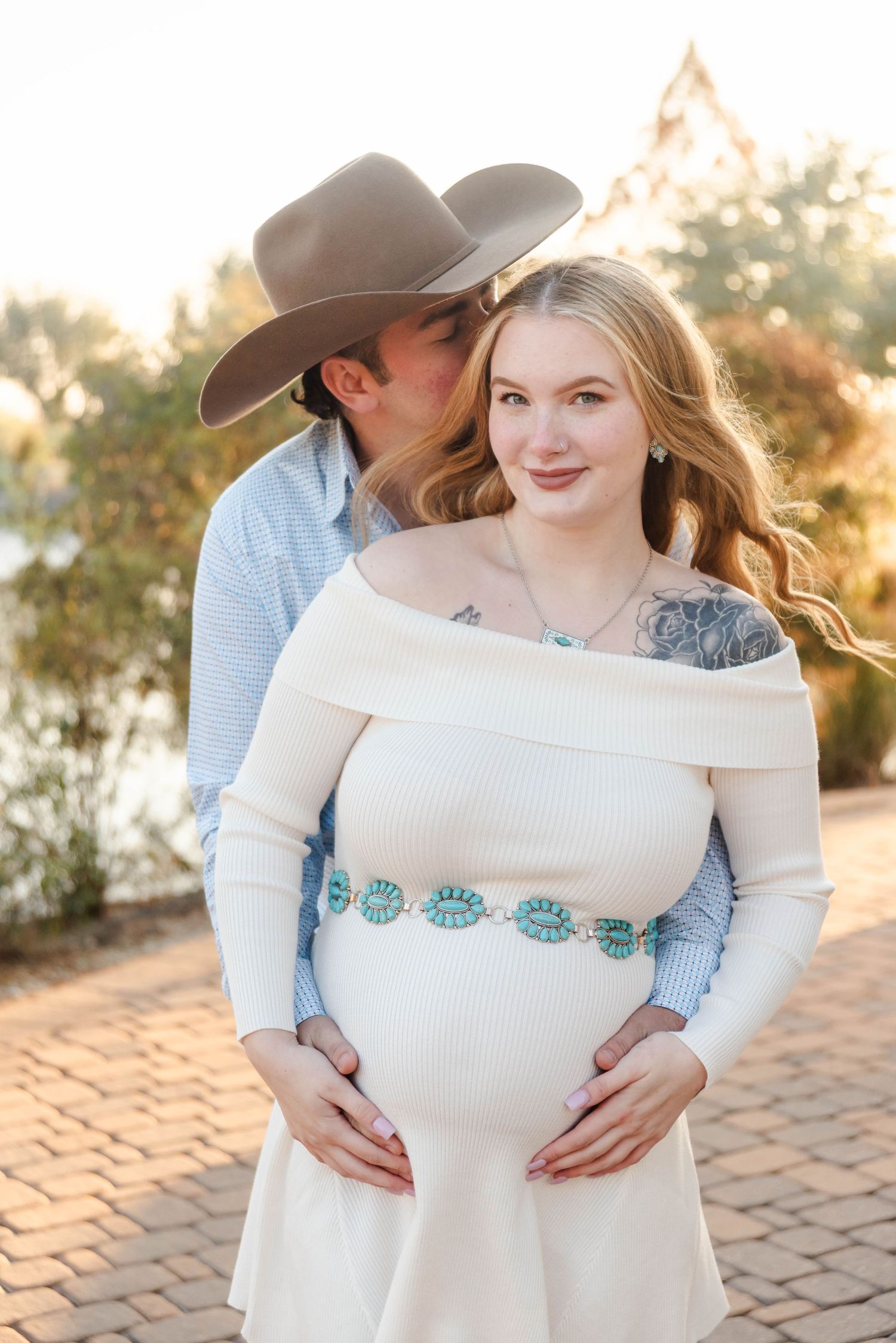 A couple smiling while holding a baby bump
