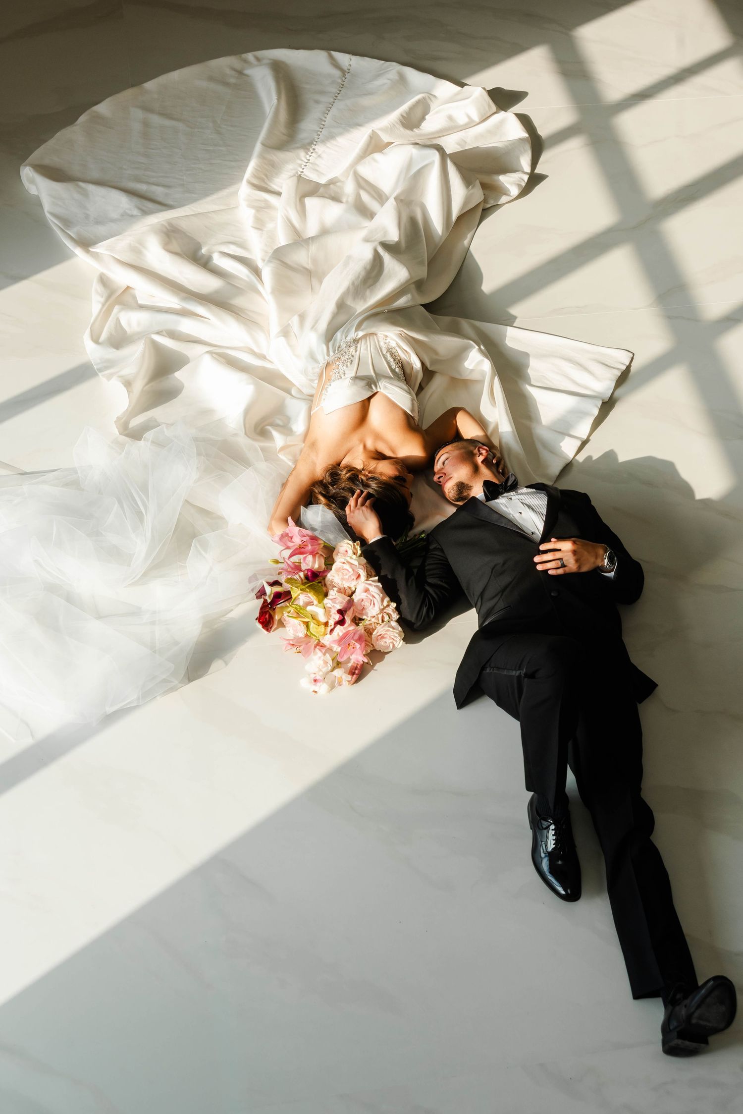 a bride and groom lay on the floor holding each others faces