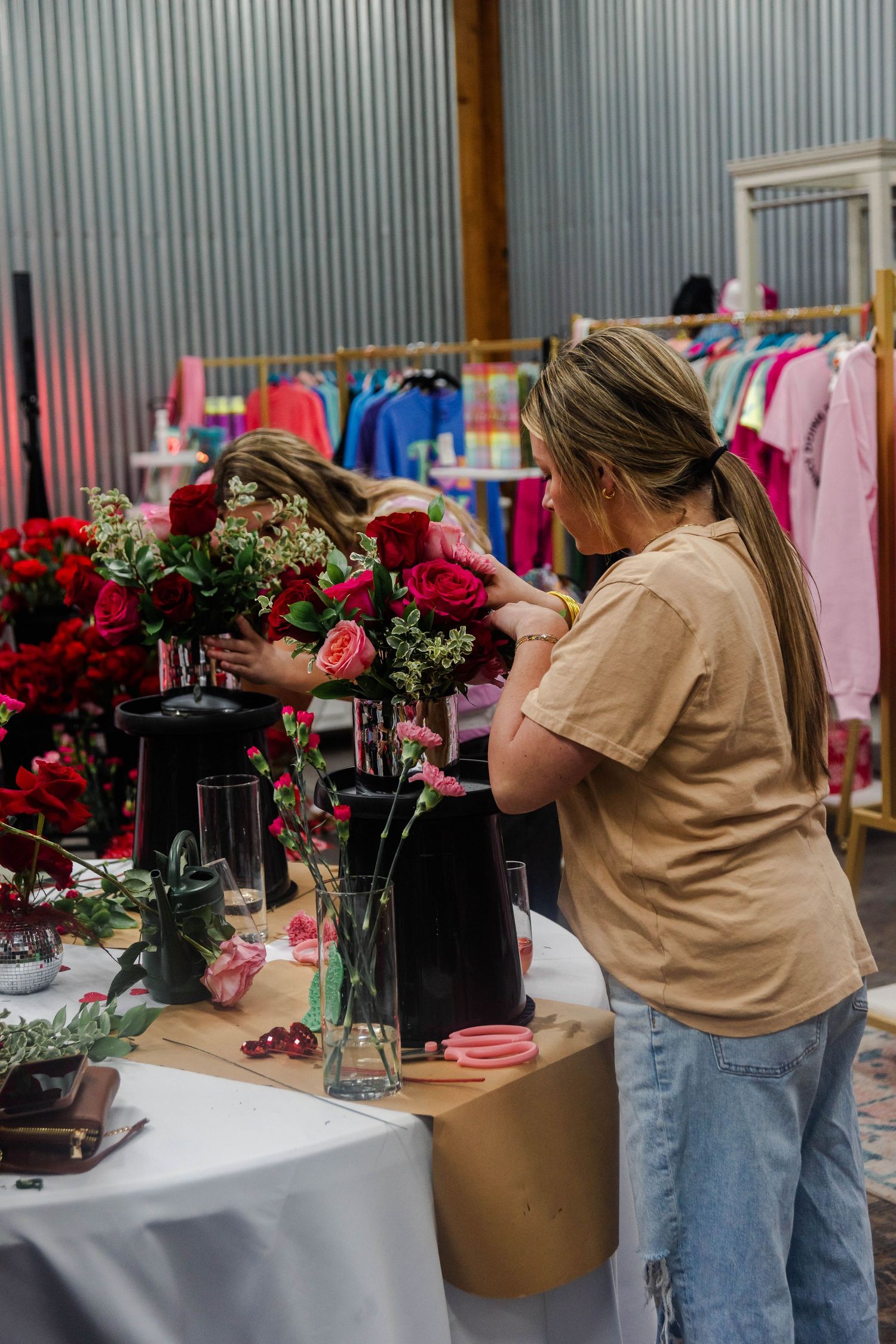 A floral arrangement workshop showing a person preparing beautiful red and pink Valentine's bouquets at a decorated table.