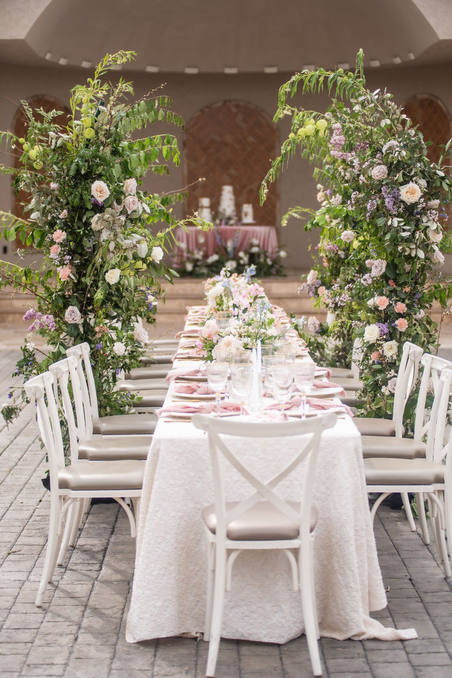 Family style table setting for a wedding with the cakes displayed behind it