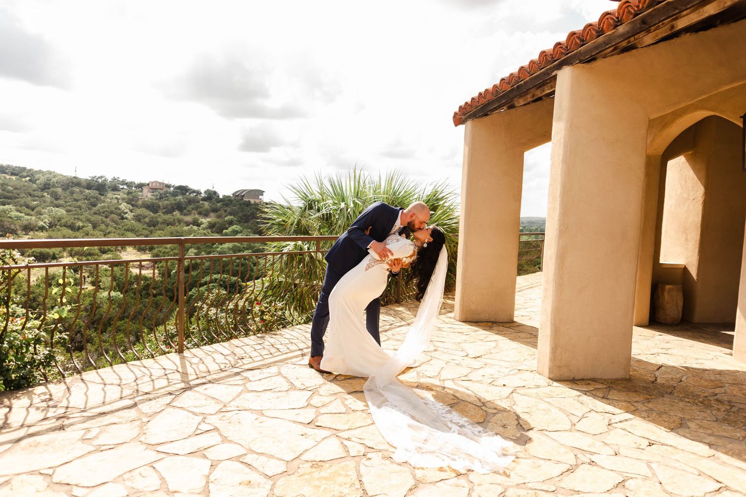 Groom dips his bride back with a kiss overlooking the Texas hill country