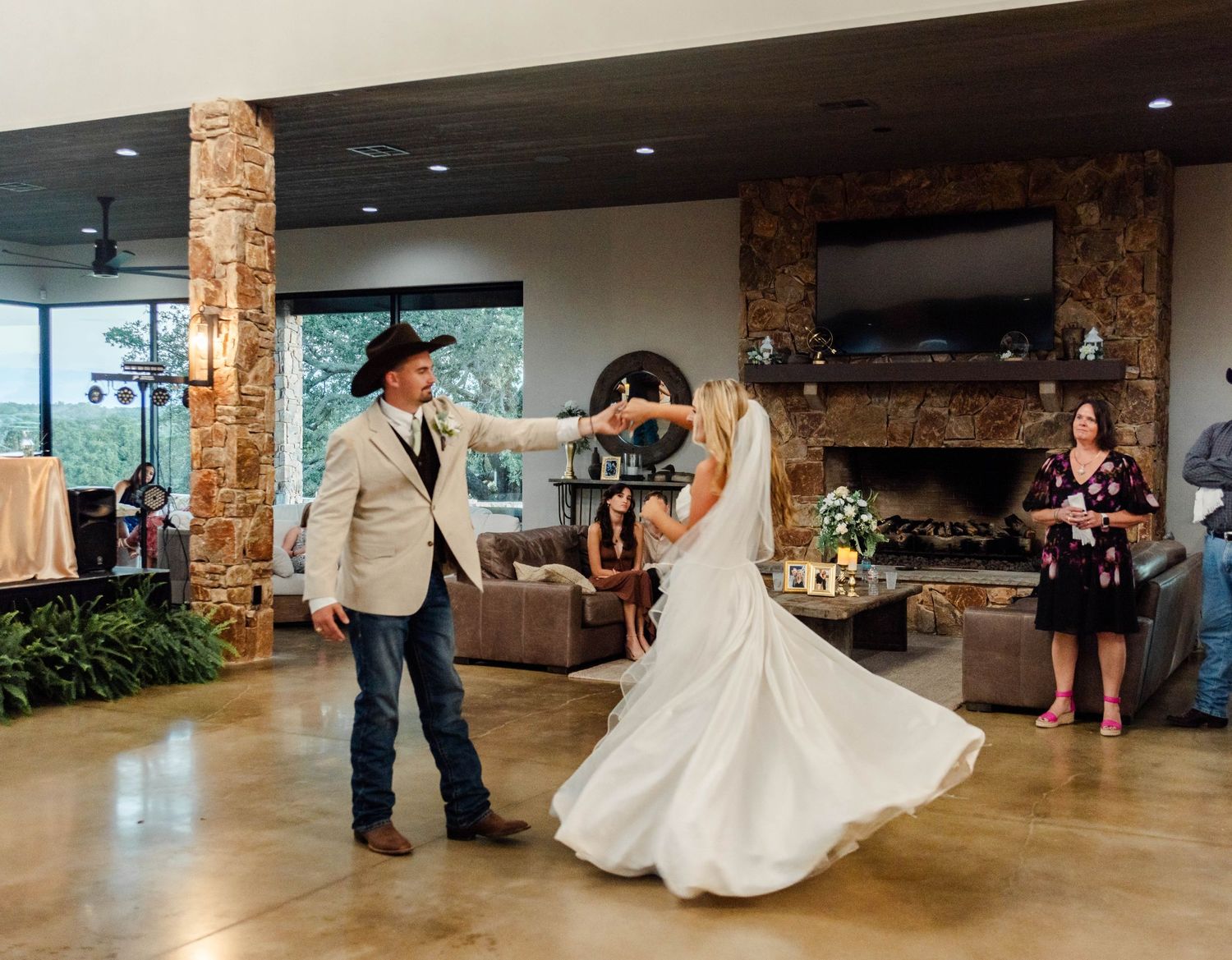 A couple shares their first dance together in an elegant rustic venue with stone pillars and natural lighting.